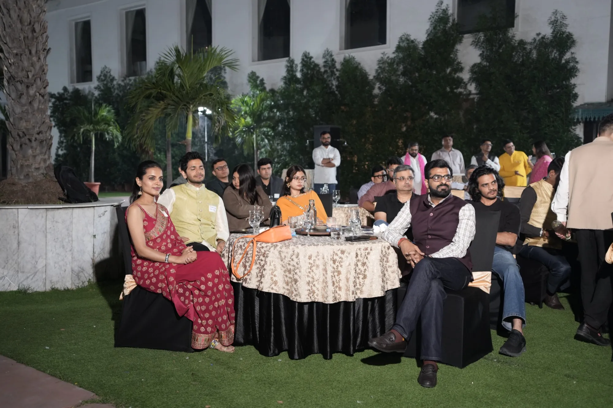 Founders seated at round tables on the lawn, listening